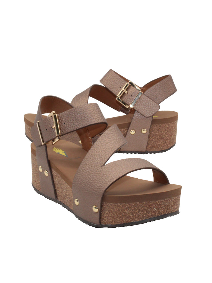 Vegan leather or heavy canvas asymmetrical upper Synthetic lining Adjustable metal buckle and metal clog studs Asymmetrical sandal with back strap Ultra comfort EVA insole Cork wedge Rubber traction outsole Approx. 2” heel height bronze