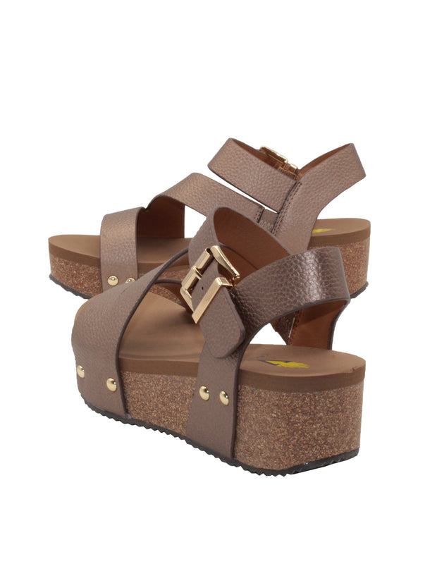Vegan leather or heavy canvas asymmetrical upper Synthetic lining Adjustable metal buckle and metal clog studs Asymmetrical sandal with back strap Ultra comfort EVA insole Cork wedge Rubber traction outsole Approx. 2” heel height bronze back