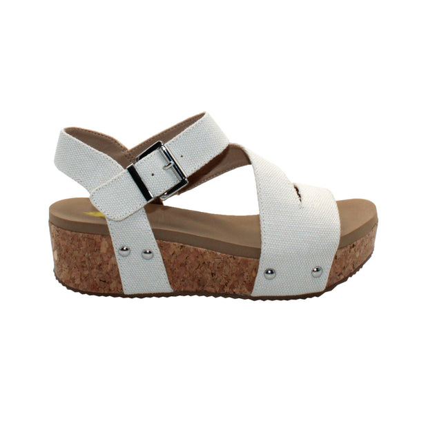 Vegan leather or heavy canvas asymmetrical upper Synthetic lining Adjustable metal buckle and metal clog studs Asymmetrical sandal with back strap Ultra comfort EVA insole Cork wedge Rubber traction outsole Approx. 2” heel height ivory side