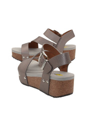 Vegan leather or heavy canvas asymmetrical upper Synthetic lining Adjustable metal buckle and metal clog studs Asymmetrical sandal with back strap Ultra comfort EVA insole Cork wedge Rubber traction outsole Approx. 2” heel height pewter back